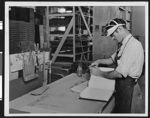 Man putting the cover on a book at the Universal Braille Press, ca.1933