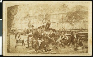 Several men in an outdoor tavern patio, some apparently drunk on the ground in Oakland City, Alameda, ca.1900