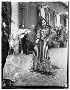 A man playing guitar as a woman dances for the "birthday of Los Angeles"