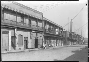 View of two-story brick buildings along a dirt road in Los Angeles's Chinatown