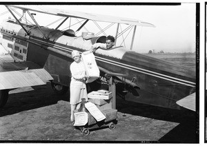 Inauguration of the Air Express Service, showing a woman handing packages to the pilot, August 31, 1927