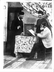 Two Los Angeles Plaza church priests with Don Antonio Coronel examining church records, ca.1885-1900