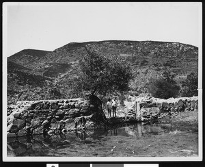 Mission San Diego de Alcala irrigation dam, showing two women standing by a puddle, 1930