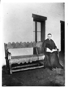 Plaza Church priest Reverend Joachim Adam, sitting on a bench, Los Angeles, ca.1890-1900