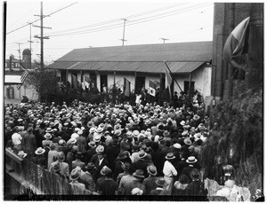 Large crowd gathered outside a large building on Olvera Street