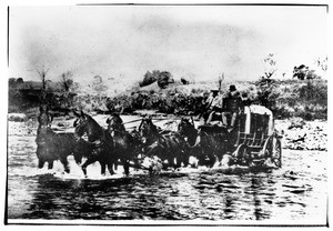 Two men riding their carriage across a river