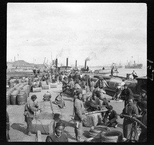 View of workers unloading goods at the Chinese waterfront, ca.1900