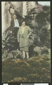 Man and woman standing by rock face, ca.1930