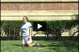 A young female soccer player heading while kneeling