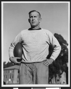 University of Southern California football coach Howard Jones holding football, hands on hips, Bovard Field, USC campus, 1933