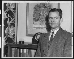 University of Southern California head football coach Jess Hill in front of Rose Bowl poster in his office, USC campus, 1955