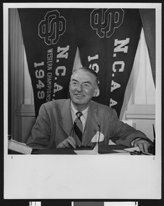 University of Southern California sports coach Sam Barry in front of USC's NCAA championship banners, USC campus, 1950