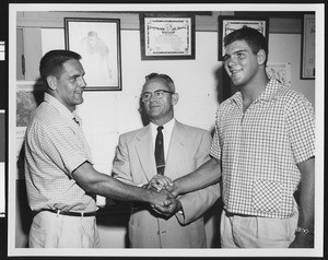 University of Southern California football coach Jess Hill looks on while the 1953 USC co-captains shake hands, USC campus, 1953