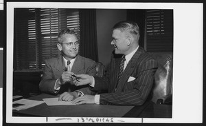 University of Southern California head football coach Jess Hill (left) takes a pen from President Fagg as they sign Hill's new football contract, USC campus, January 1951