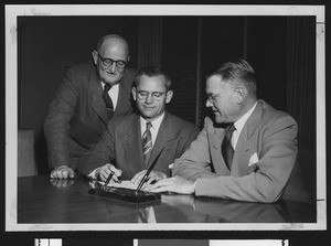 University of Southern California football coach Jess Hill signs a new three-year contract while Bill Hunter and President Fagg look on, USC campus, December 1951