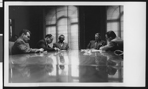 Press conference for new University of Southern California head football coach Jess Hill, with three reporters taking notes, January 1951