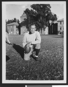 University of Southern California football coach Howard Jones, holding football on Bovard Field while on one knee, USC campus, 1933