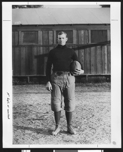 Dean Cromwell, famed University of Southern California sports coach, wearing a football uniform in 1908 standing on Bovard Field, USC campus, Los Angeles