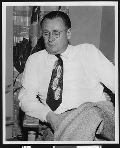 University of Southern California football coach Jeff Cravath sitting in chair wearing a tie with football shapes on it, Los Angeles, circa 1950