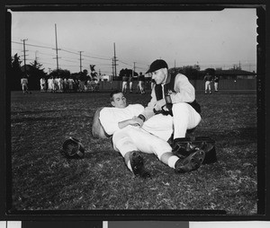 University of Southern California sports trainer Kearney Reeb examining the wrist of quarterback Jim Contratto, Bovard Field, 1951