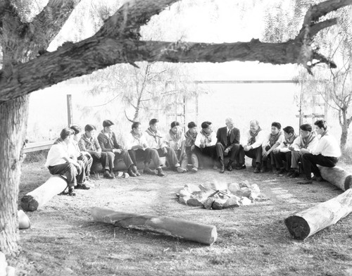 Members of Boy Scout troop sit around campfire