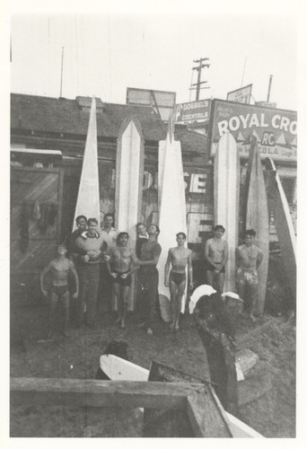 Harry Murray, Jeep Allen, Fred Hunt, Dave Steward, Duke Horan, Bill Lidderdale, E. J. Oshier, unidentified surfer, Sam Maugeri in front of surfboards, Cowell Beach