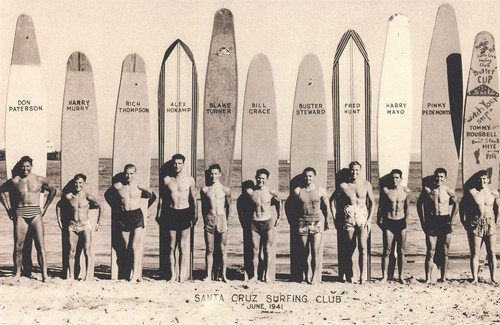 Club surfers standing in front of surfboards: Don Patterson, Harry Murray, Rich Thompson, Alex Hokamp, Blake Turner, Bill Grace, Buster Steward, Fred Hunt, Harry Mayo, Pinky Pedemonte, Tommy Roussel at Cowell Beach