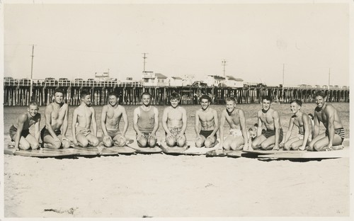 Santa Cruz Surfing Club members Rich Thompson, Alex Hokamp, Blake Turner, Bill Grace, Dave "Buster" Steward, Tommy Roussel, Harry Mayo, Fred Hunt, Alex "Pinky" Pedemonte, Harry Murray, and Don "Bosco" Patterson at Cowell Beach