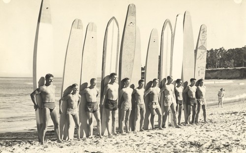 Club surfers standing in front of surfboards: Don Patterson, Harry Murray, Rich Thompson, Alex Hokamp, Blake Turner, Bill Grace, Dave "Buster" Steward, Fred Hunt, Harry Mayo, Pinky Pedemonte, Tommy Roussel at Cowell Beach