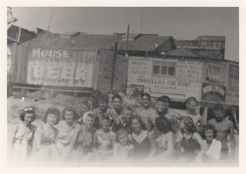 Front- Marion Frykland, Betty Eaton, Betty Frapwell, Carol Stanley, Joan Harris, Beverly Graham, Helen Graham, Sally Coen, Barbara Pattee, Carol Wood. Middle- Dave Sachau, 3 unidentified surfers, Jerry Owens, Chuck Lewis, Bill Lidderdale, Rod Atchison, Harry Mayo on Cowell Beach