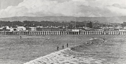 Unidentified surfers on waves with views wharf and boardwalk