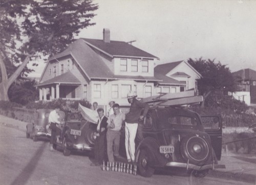 Unidentified surfers and E. J. Oshier in front of automobiles at Seabright Beach