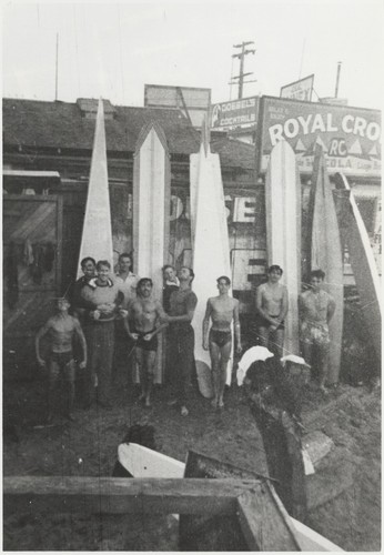 Surfers in front of board house: far left, Harry Murray, Eugene "Jeep" Allen, Dave "Buster" Steward, Claude "Duke" Horan, unidentified, E. J. Oshier, Chet Mayo, Sam Maugeri