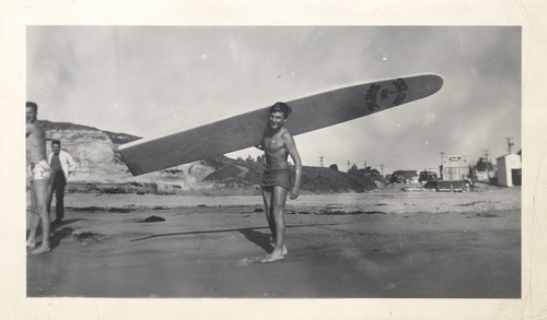 Alex Hokamp carrying surfboard, Harry Mayo, and Harry Murray at Cowell Beach