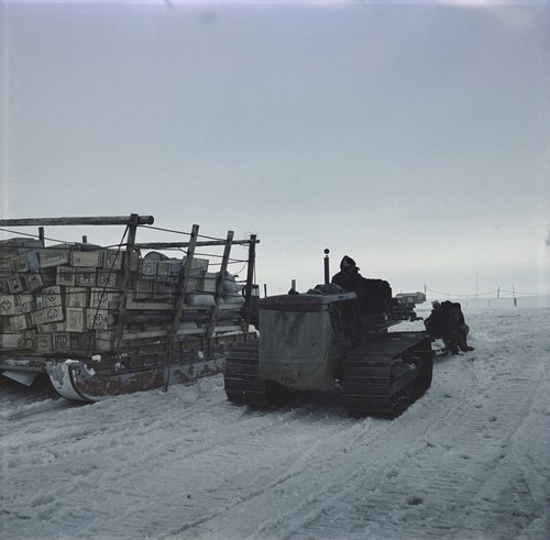 Tractor sledge train unloading supplies from research ship Ob