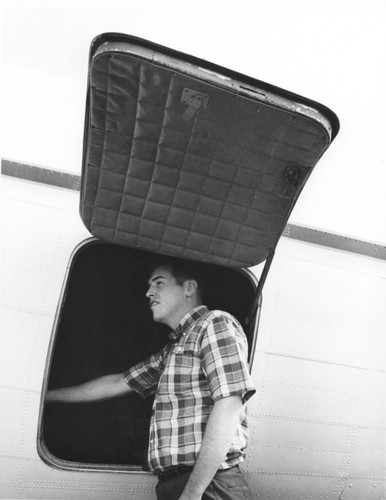 In 1962 Applied Oceanography Group (AOG) at Scripps Institution of Oceanography leased this DC-3 airplane. This photo shows an unidentified man looking inside the door hatch of the plane. Later the plane would be given to them for continued research; AOG then mounted a infrared radiometer to measure heat flow from the ocean in the plane. With the airplane it was possible to survey 10,000 square miles of sea surface in 24 hours. Circa 1965