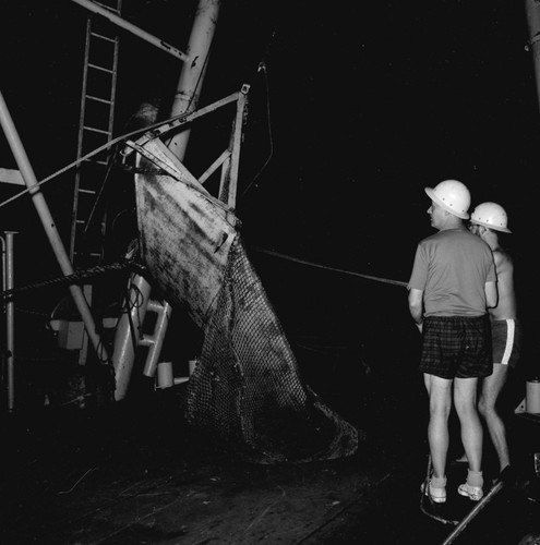 [Oceanographers preparing trawl for deployment at night]