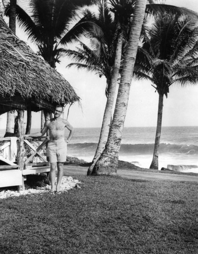 Walter Heinrich Munk, near the fale he lived and worked in while in American Samoa where he worked to track storm driven waves across the Pacific Ocean using digital equipment in field experiments. 1963