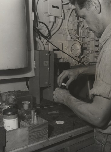 Technician preparing sterile water sample, perhaps for microbiological work for Dick Morita and Claude ZoBell. Transpac Expedition, 1953