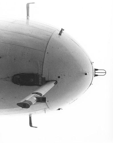 In 1962 Applied Oceanography Group (AOG) at Scripps Institution of Oceanography leased this DC-3 airplane. This photo shows the front bottom nose view of the aircraft with the camera mounting. Later the plane would be given to them for continued research; AOG then mounted an infrared radiometer to measure heat flow from the ocean in the plane. With the airplane it was possible to survey 10,000 square miles of sea surface in 24 hours. Circa 1965