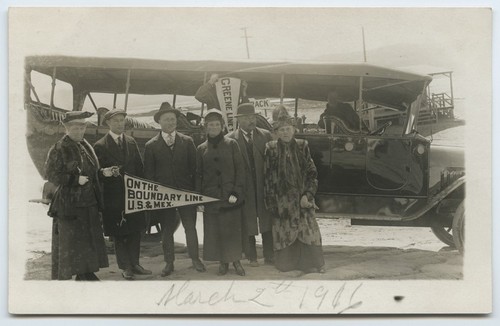 Tijuana visitors near tour bus with "On the boundary line U.S. & Mex" pennant