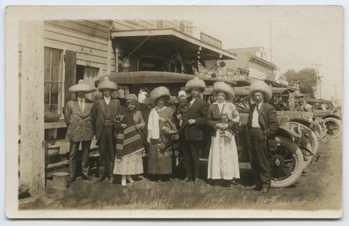 Tourists in sombreros near U.S.-Mexico border station, near parked automobiles