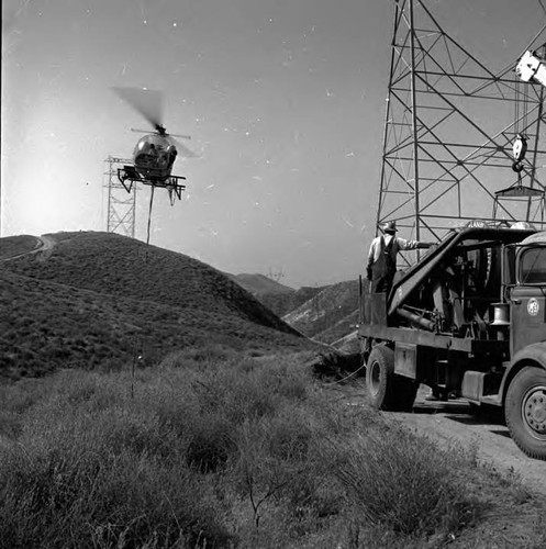 Stringing cable to towers by helicoper