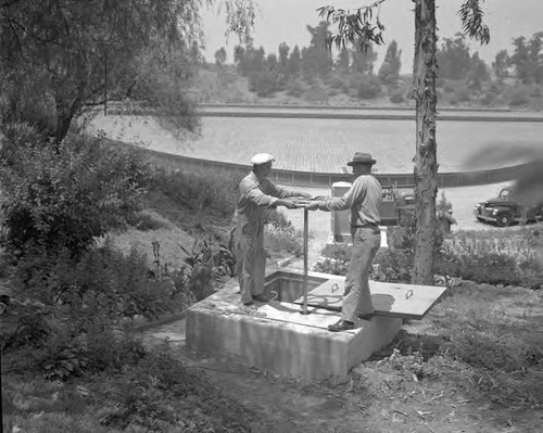 Ellis Davey (Metropolitan Water District) and B. W. Weaver (Water Bureau) turn 30" valve that lets first Colorado River water into city system - Ascot Reservoir