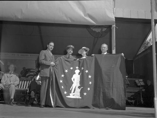 Minute Man flag earned by Department employees is accepted from Howard D. Mills (left) by Marc Huber, Jessie Poole and Charles Aldis