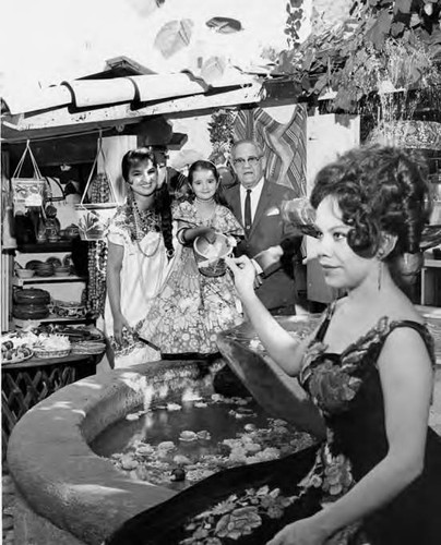 Olvera Street fountain with Erma Tapia and possibly her daughter and Consuelo de Sousa and an unidentified man standing at fountain