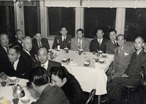 Photograph of men seated around tables