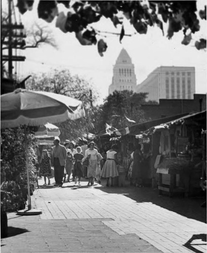 Crowds on Olvera Street with City Hall and Federal Building in background, looking north to south