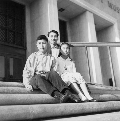 Show Fung Quan (father) and Henry and Susan, his children. They are Steve Mar's maternal grandfather, uncle and mother seated on the steps of the Los Angeles County National Museum