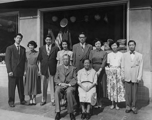 Formal photo of Gee Kee Ward, Yee Good Gal, their four grown-up children and new spouses in front of the newly completed Sam Ward Co. building on Hill Street; taken in Los Angeles